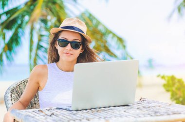 Sahilde içinde laptop çalışan genç kadın. Serbest çalışma
