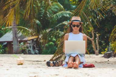 Young woman freelancer working in laptop on the beach. Freelance work clipart