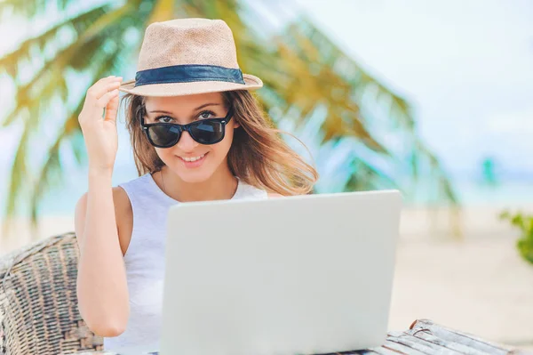 Νεαρή γυναίκα που εργάζεται σε φορητό υπολογιστή στην παραλία. Δουλειά freelance — Φωτογραφία Αρχείου