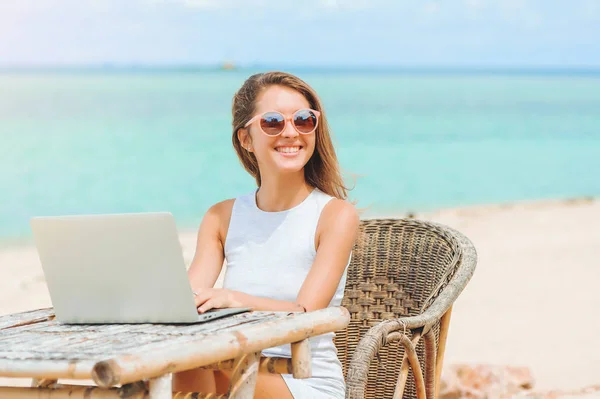 Mujer sexy joven usando el ordenador portátil en la playa. Trabajo independiente —  Fotos de Stock