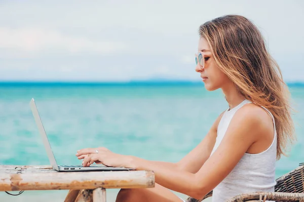 Mujer sexy joven usando el ordenador portátil en la playa. Trabajo independiente — Foto de Stock