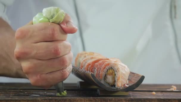 Наливание васаби на деревянный стол с суши-роллами — стоковое видео