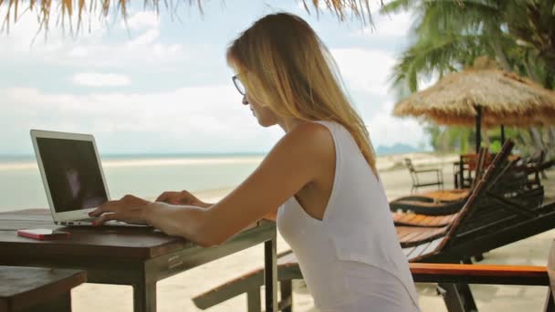 Giovane donna freelance seduta al lettino con un computer portatile — Video Stock