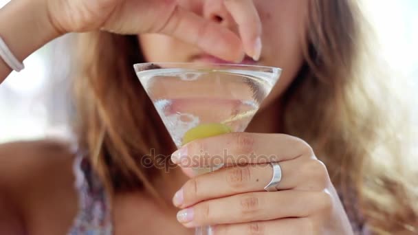 Het meisje houdt een glas met een martini cocktail en olijven. — Stockvideo