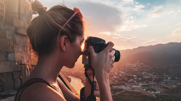 Kadın fotoğrafçı, gün batımında dağ manzarasının fotoğraflarını çekiyor.