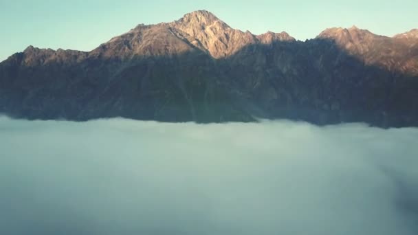 Повітряний дрон політ над гірським хребтом через хмари на заході сонця 4K — стокове відео