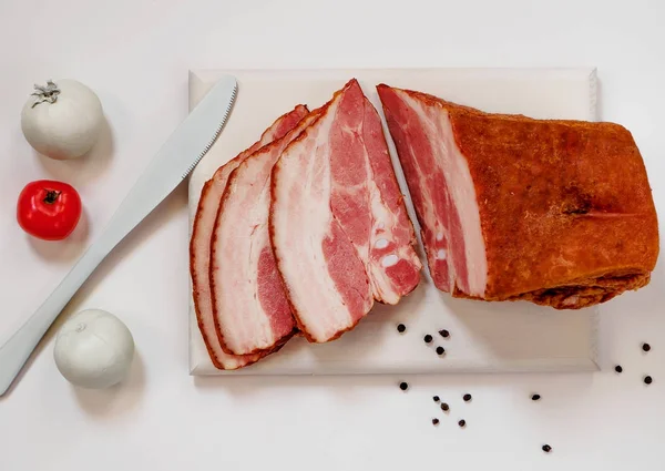 Bacon defumado na placa de corte branca — Fotografia de Stock