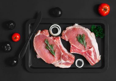 Ham taze domuz biftek bir siyah siyah arka plan, düz siyah renk kavramı üzerine sac pişirme