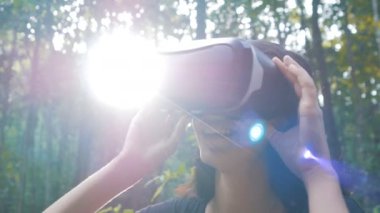 güzel genç esmer kadın sanal gerçeklik gözlük ormanda kullanır.