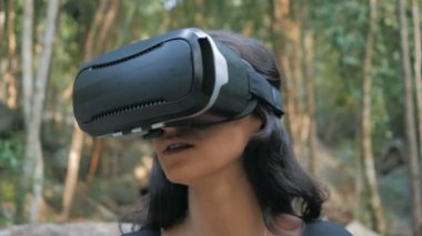 güzel genç esmer kadın sanal gerçeklik gözlük ormanda kullanır.
