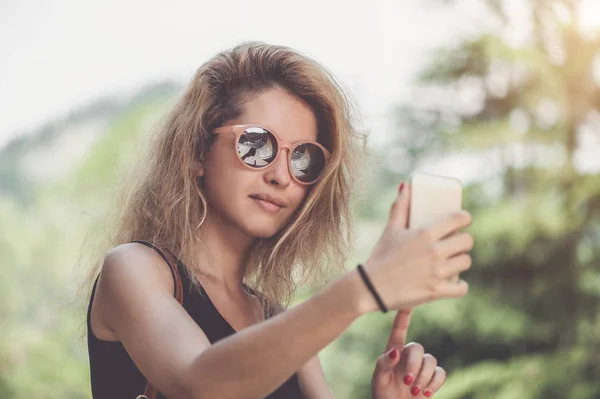 Closeup portrait of young beautiful woman in sunglasses with long blonde curly hair doing selfie photos — Stock Photo, Image