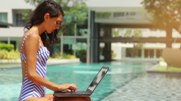 Modelka pracovat na volné noze v plaveckém bazénu na notebooku. 3 výstřely — Stock video
