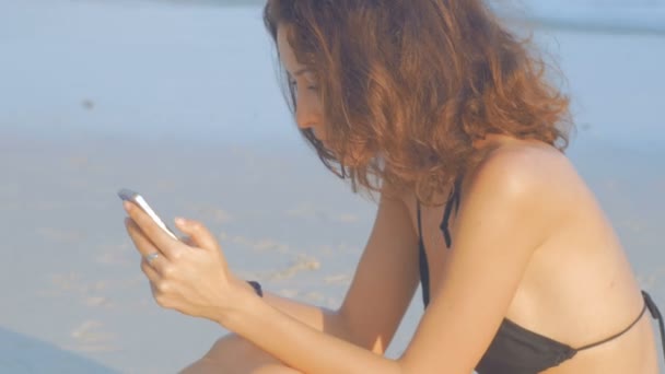 Donna sms con il suo telefono sulla spiaggia — Video Stock