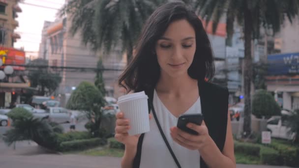 Vrouw met smartphone en wandelen in de stad, steadicam schot koffie — Stockvideo