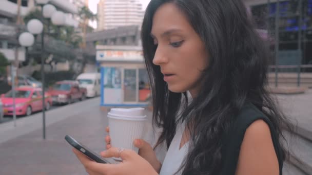 Kvinna med smartphone och kaffe promenader i staden, steadicam sköt — Stockvideo