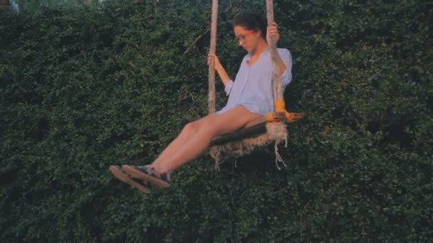 Jeune belle femme s'amuse sur une balançoire tropicale dans la lumière du coucher du soleil — Video