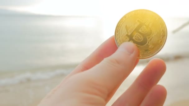 Manos de hombre celebración criptomoneda BTC Bitcoin monedas en la playa — Vídeos de Stock