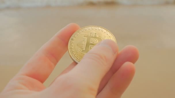 Man händer som håller krypto valuta Btc Bitcoin mynt på stranden — Stockvideo