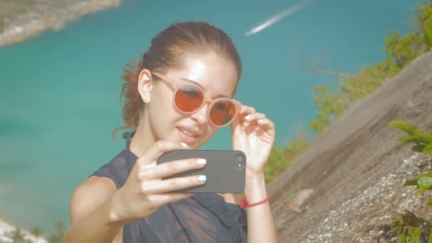 Vacker flicka traveler tar en selfie med havsutsikt på en höjd i slowmo — Stockvideo