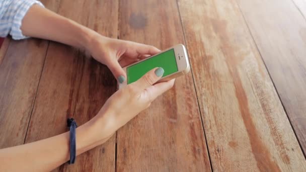 Mulher usando telefone inteligente com tela verde no fundo da mesa de madeira — Vídeo de Stock