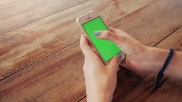 Mujer usando teléfono inteligente con pantalla verde sobre fondo de mesa de madera — Vídeos de Stock