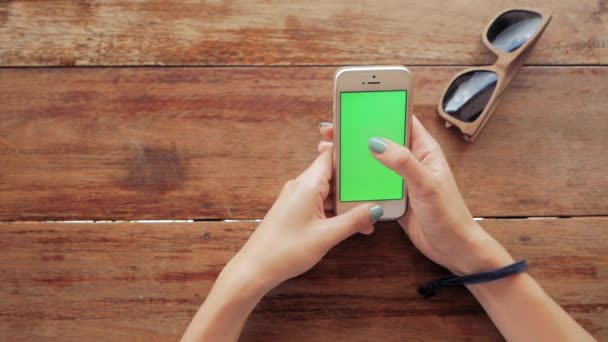 Mulher usando telefone inteligente com tela verde no fundo da mesa de madeira — Vídeo de Stock