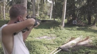 Beyaz ceketli adamı bir yaylı tüfek ateş ediyor