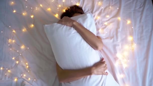 Sleepy funny girl covering face with pillow. Playing with pillow on bed — Stock Video