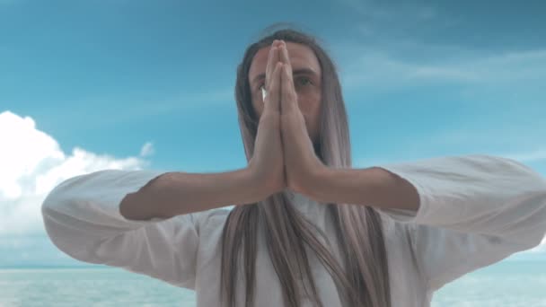 Man gör yoga på stranden på blå himmel bakgrund — Stockvideo