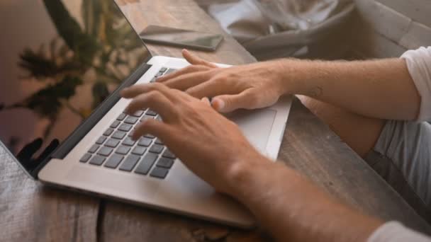 Närbild av manliga händer att skriva på laptop i tropiska café — Stockvideo