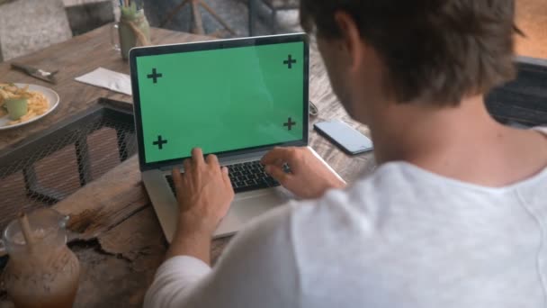Крупним планом чоловічі руки, що працюють на ноутбуці з зеленим екраном в кафе — стокове відео