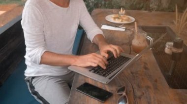 Açık kafede dizüstü bilgisayar üzerinde çalışan genç adam serbest meslek