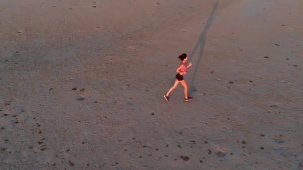 サンセット ビーチでジョギングする若い女性。撮影、スローモーション空中ドローン — ストック動画