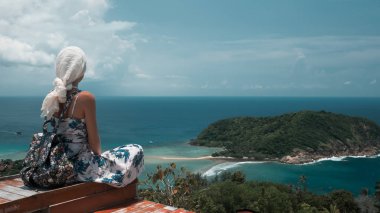 Genç turist kadın güzel deniz koyu manzara bir bakış açısı üzerinde oturuyor