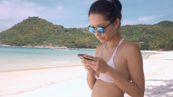 Жінка використовує мобільний телефон на пляжі — стокове відео