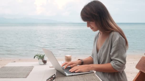 해변에서 노트북에서 그녀의 작품을 완성 하는 행복 한 젊은 아름 다운 여자 — 비디오
