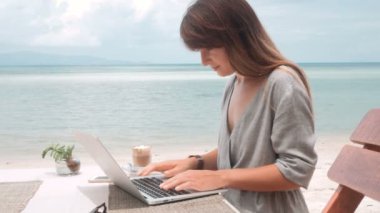Mutlu genç kadın kamera dönen laptop açık havada kafede çalışıyor