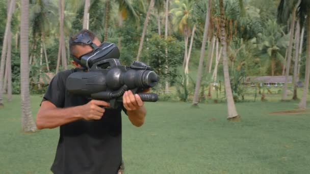 Человек с оружием играет в игру виртуальной реальности в джунглях — стоковое видео
