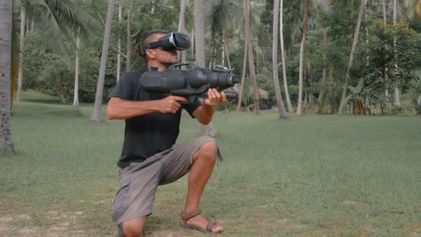 Homme armé jouant au jeu de réalité virtuelle dans la jungle — Video