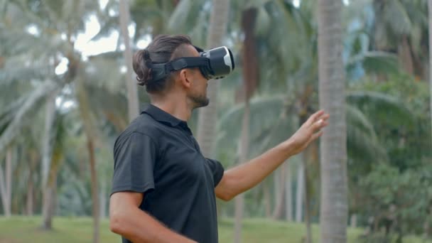 Man met hoofdtelefoon van virtuele realiteit in de jungle — Stockvideo