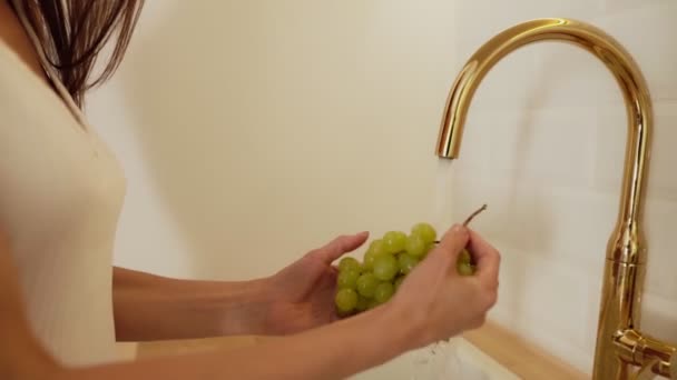 Vacker sexig kvinna i vita underkläder tvätt Grape. Handhållna färska druvor under rinnande vatten i köket diskbänk i Slowmotion. — Stockvideo