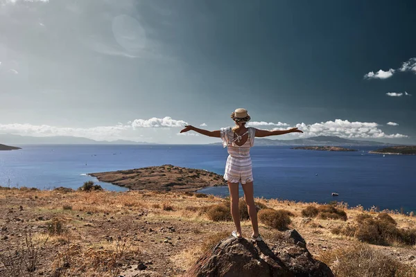 Jeune voyageuse debout sur un rocher et levant les bras — Photo