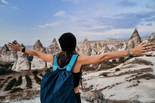 Güzel turist kadın kollarını kaldırıyor ve Goreme köyündeki Aşk Vadisi 'nin manzarasını sunuyor..