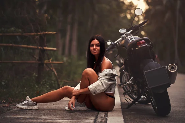 Mulher sexy com uma motocicleta preta no estilo piloto de café — Fotografia de Stock