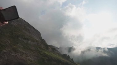 Genç bir çift uçurumda sarılıyor ve selfi bir fotoğraf çekiyor.