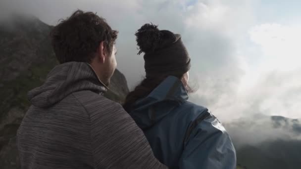 Un jeune couple heureux serrant dans ses bras et debout sur une falaise dans les montagnes impatient — Video