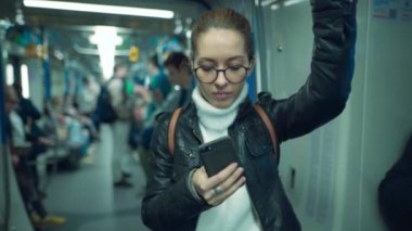 Metrodaki kadın akıllı telefonunu kullanıyor.