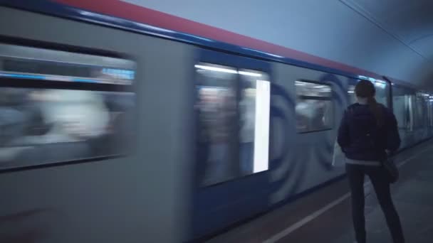 Mulher em uma plataforma de metrô como um trem chega — Vídeo de Stock