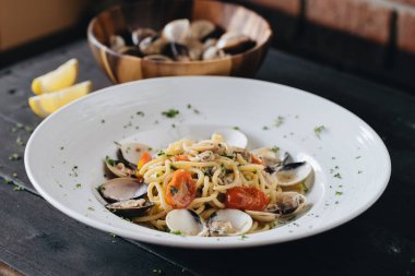 Siyah arka planda beyaz tabakta istiridyeli makarna. Akdeniz usulü lezzetli yiyecekler. Üst görünüm