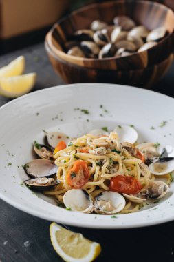 Siyah arka planda beyaz tabakta istiridyeli makarna. Akdeniz usulü lezzetli yiyecekler. Üst görünüm